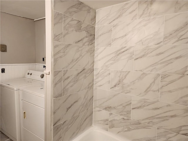 bathroom with a bathing tub, washing machine and clothes dryer, and vanity