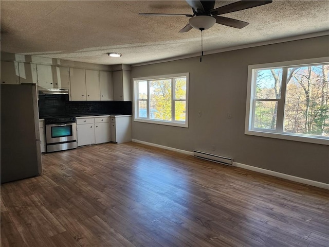 kitchen with hardwood / wood-style flooring, baseboard heating, white cabinetry, appliances with stainless steel finishes, and tasteful backsplash