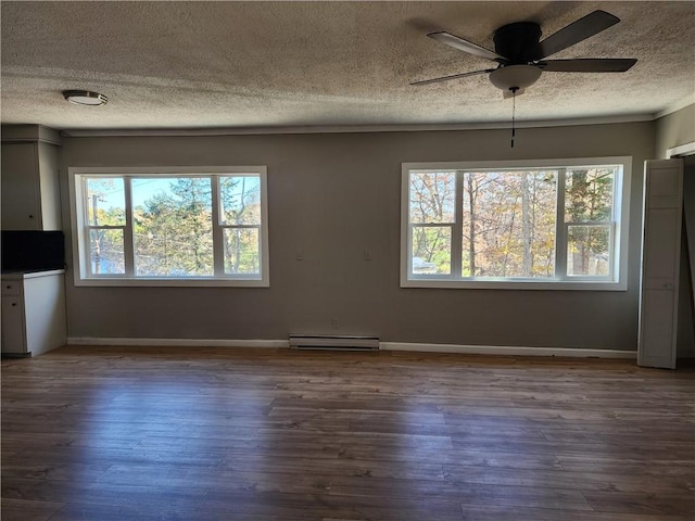 unfurnished dining area featuring ceiling fan, wood-type flooring, a wealth of natural light, and a baseboard heating unit