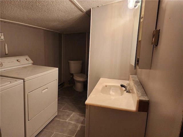 bathroom with vanity, toilet, washer and dryer, and a textured ceiling