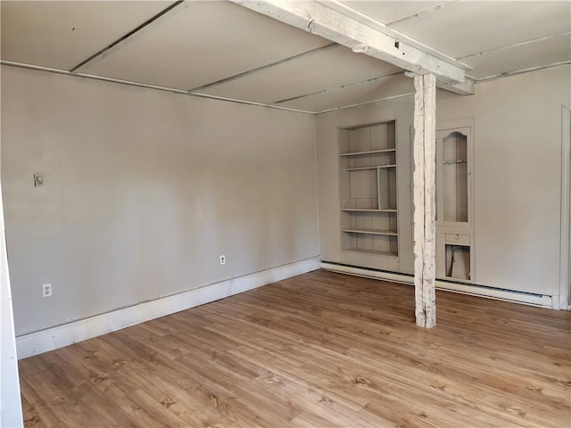 basement with hardwood / wood-style floors, built in features, and a baseboard heating unit