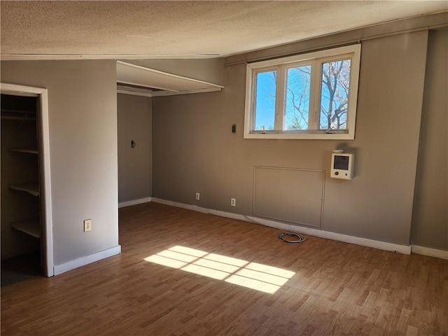 unfurnished bedroom with wood-type flooring, a closet, and a textured ceiling