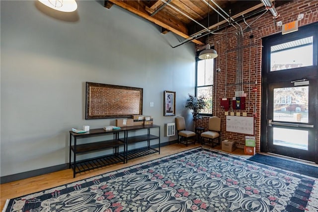 interior space with brick wall, a towering ceiling, and hardwood / wood-style floors