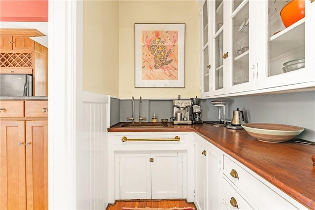 bar with white cabinetry, stainless steel fridge, and sink