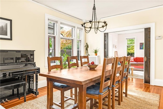 dining area with a healthy amount of sunlight, a chandelier, and light hardwood / wood-style flooring