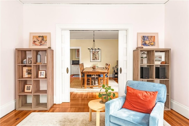 sitting room featuring an inviting chandelier, hardwood / wood-style floors, and crown molding