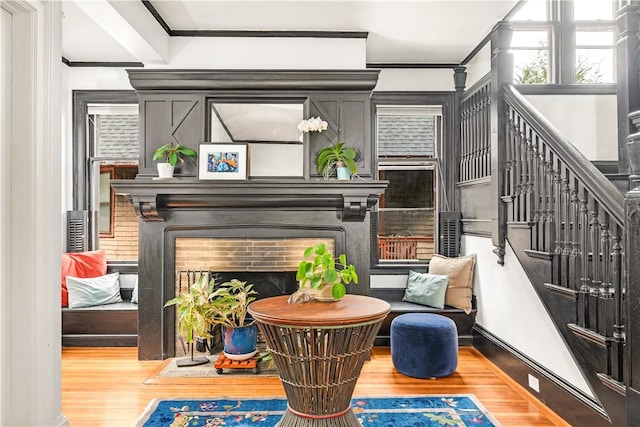 living area with wood-type flooring, crown molding, and a fireplace