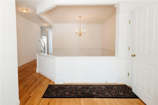 interior space featuring an inviting chandelier, decorative light fixtures, ornamental molding, and hardwood / wood-style flooring