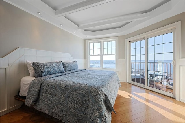 bedroom with beam ceiling, a wainscoted wall, and wood finished floors