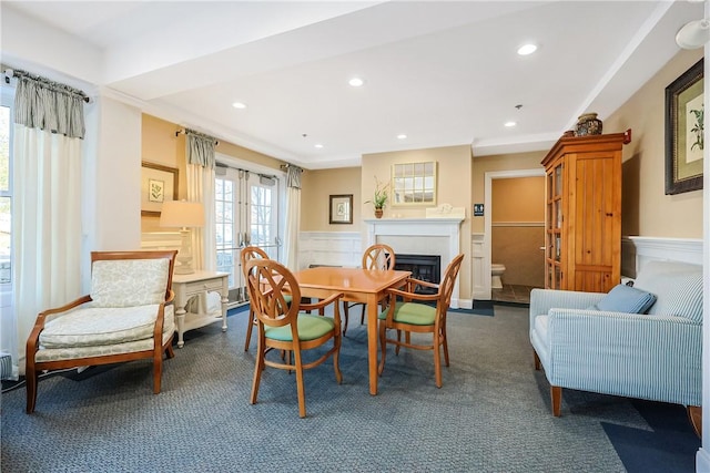 carpeted dining space with recessed lighting, a fireplace, a wainscoted wall, and french doors