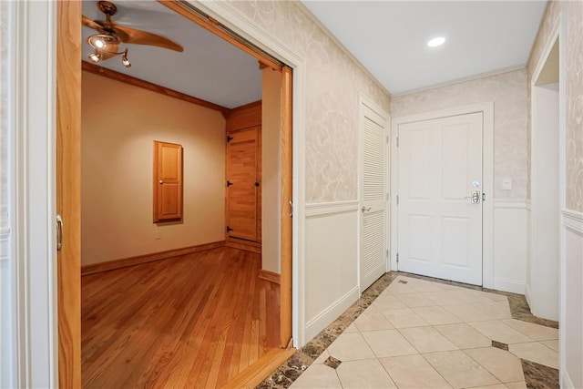 corridor featuring light wood-type flooring, baseboards, and ornamental molding