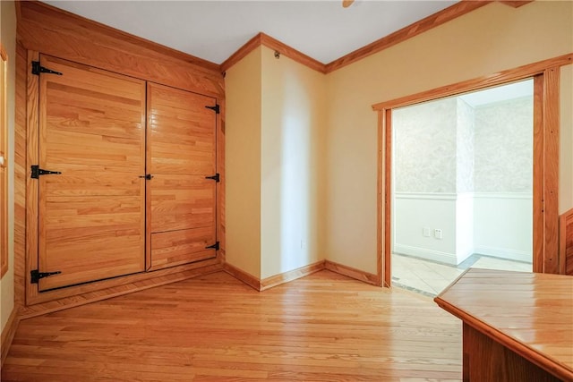 interior space with baseboards, light wood-type flooring, and ornamental molding