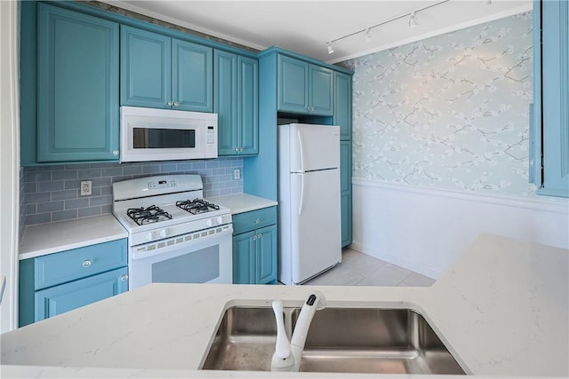 kitchen with blue cabinetry, a wainscoted wall, white appliances, and wallpapered walls