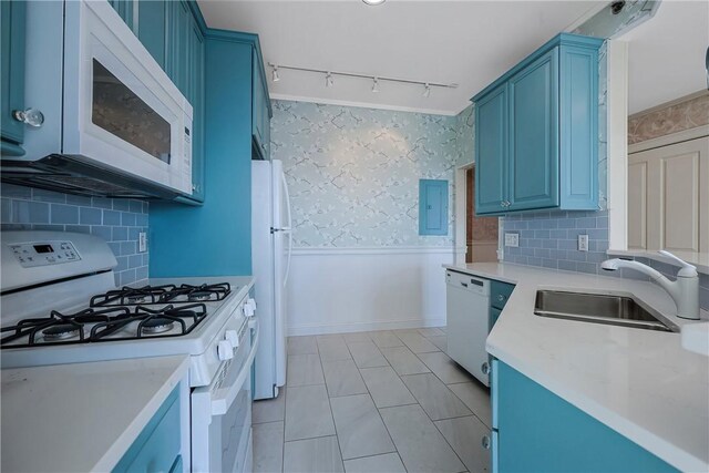 kitchen with blue cabinetry, white appliances, wallpapered walls, and a sink