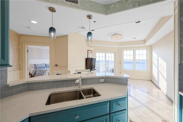 kitchen featuring a sink, blue cabinets, light stone countertops, and hanging light fixtures