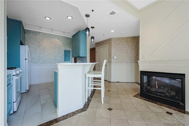 kitchen featuring wallpapered walls, wainscoting, a kitchen breakfast bar, white appliances, and blue cabinets