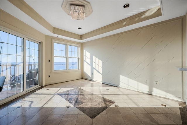 tiled spare room with a tray ceiling, crown molding, and baseboards