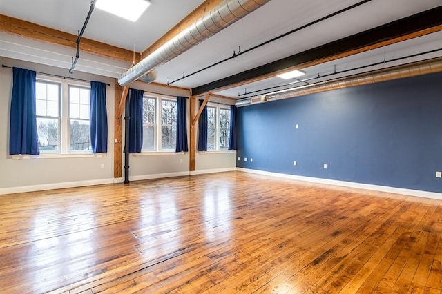 empty room featuring beamed ceiling and light hardwood / wood-style floors