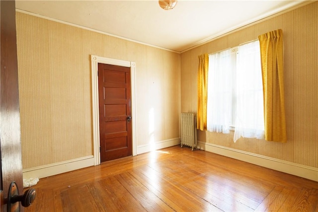 spare room with crown molding, radiator, and hardwood / wood-style flooring