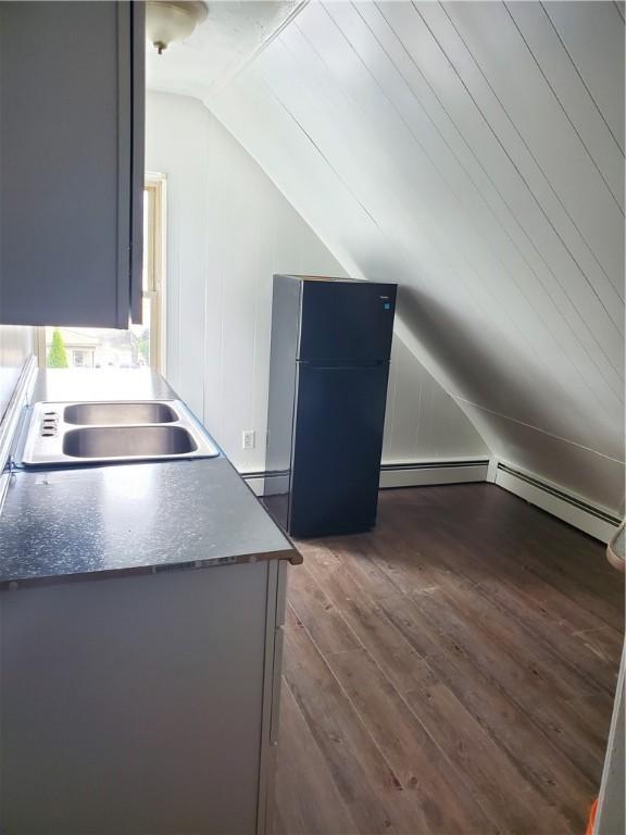 kitchen featuring black fridge, dark hardwood / wood-style flooring, sink, and vaulted ceiling