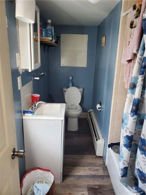 full bathroom with hardwood / wood-style flooring, vanity, a baseboard heating unit, shower / tub combo, and toilet