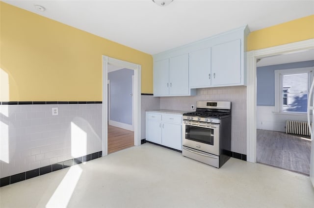 kitchen with stainless steel gas stove, radiator heating unit, and white cabinets