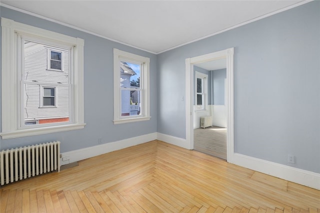 empty room with radiator, crown molding, and light parquet flooring