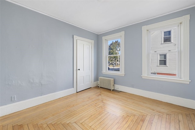 unfurnished room featuring radiator, crown molding, and light parquet floors