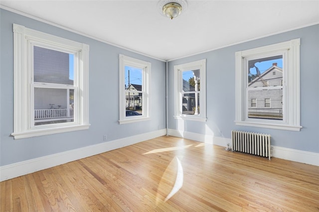 empty room with crown molding, radiator, and light hardwood / wood-style floors