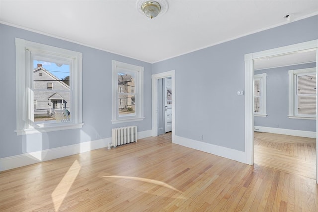 unfurnished room with radiator heating unit and light wood-type flooring