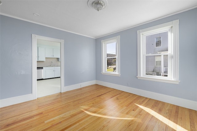 spare room featuring sink, ornamental molding, and light wood-type flooring