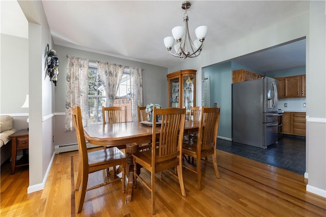 dining area with wood-type flooring, a baseboard heating unit, and a notable chandelier