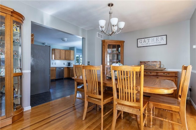 dining area with wood-type flooring and a notable chandelier