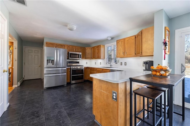 kitchen featuring appliances with stainless steel finishes, sink, a kitchen breakfast bar, baseboard heating, and kitchen peninsula