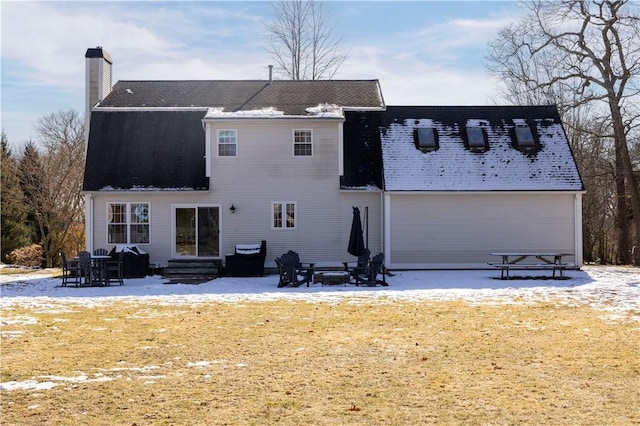 snow covered rear of property with a patio and an outdoor fire pit