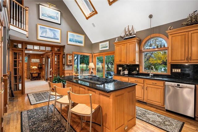 kitchen featuring appliances with stainless steel finishes, decorative light fixtures, sink, dark stone countertops, and a center island