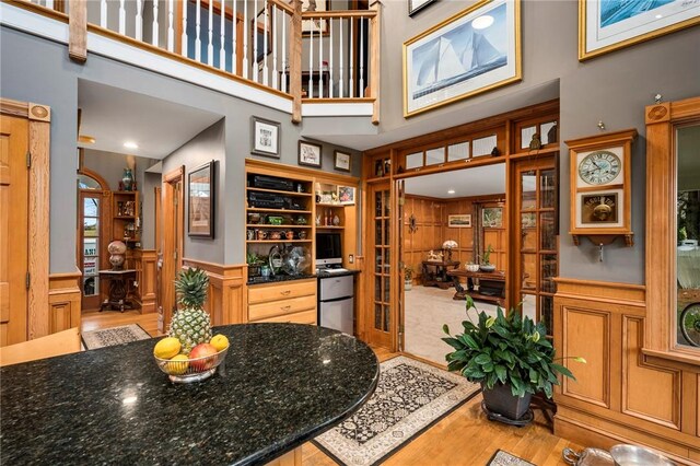 kitchen with fridge, a high ceiling, french doors, dark stone counters, and light wood-type flooring