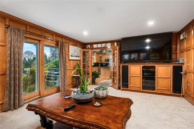 living room featuring wooden walls and light carpet