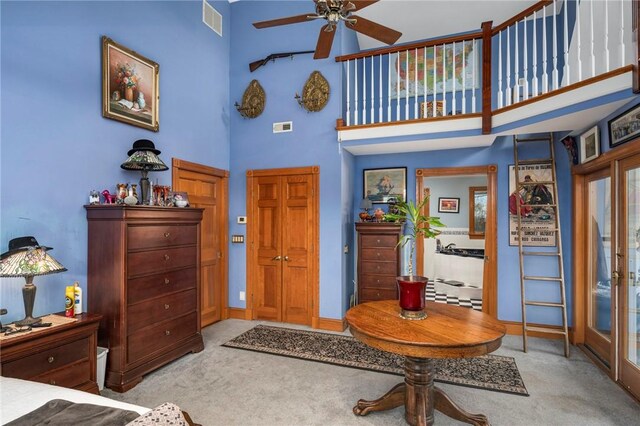 entryway featuring a high ceiling, light colored carpet, and ceiling fan