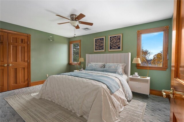 carpeted bedroom with multiple windows, radiator heating unit, and ceiling fan