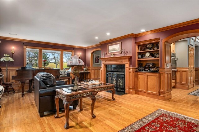 living room with crown molding, a fireplace, and light hardwood / wood-style floors