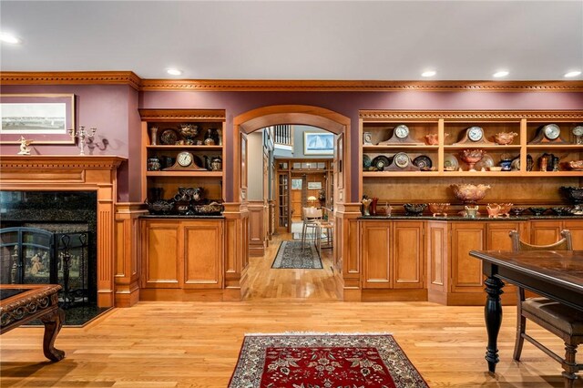 bar featuring crown molding, a high end fireplace, and light wood-type flooring