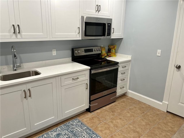 kitchen with light tile patterned floors, stainless steel appliances, light countertops, white cabinetry, and a sink