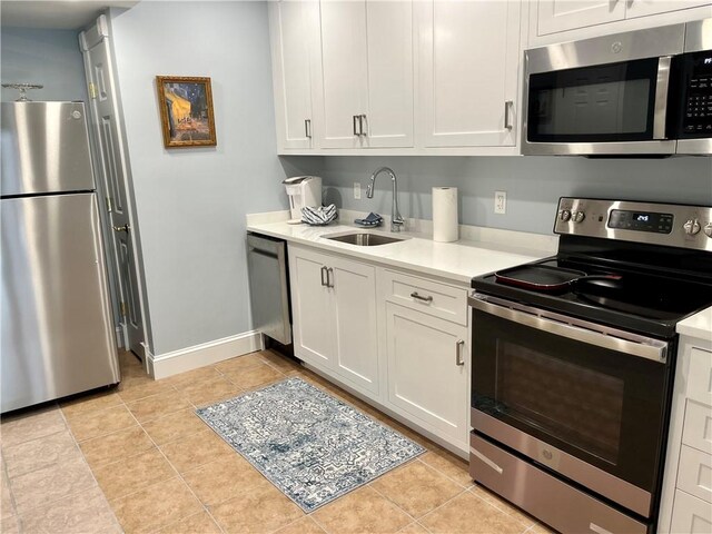 kitchen with sink, light tile patterned floors, white cabinets, and appliances with stainless steel finishes