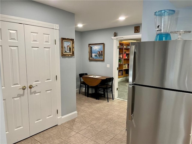 kitchen with freestanding refrigerator, light tile patterned flooring, baseboards, and recessed lighting