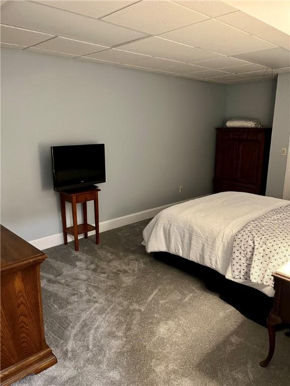 bedroom featuring a drop ceiling and dark carpet