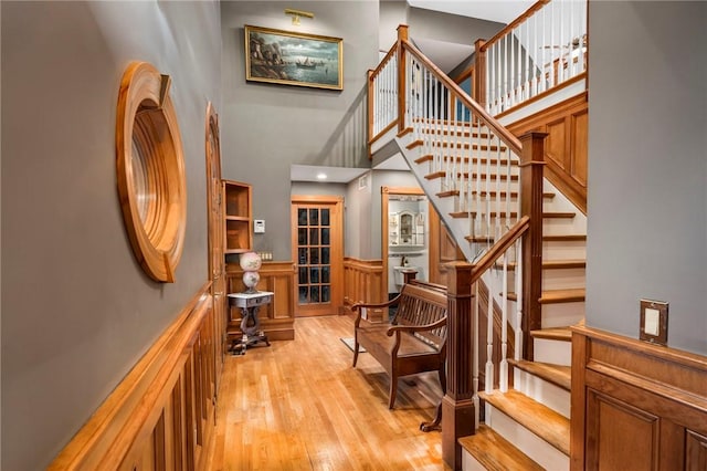 stairs with a high ceiling, a wainscoted wall, and hardwood / wood-style floors