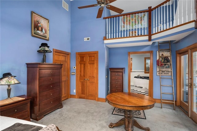 interior space featuring visible vents, a towering ceiling, carpet flooring, ceiling fan, and baseboards