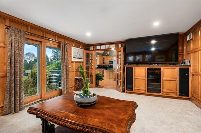 living area with light carpet, recessed lighting, and wooden walls