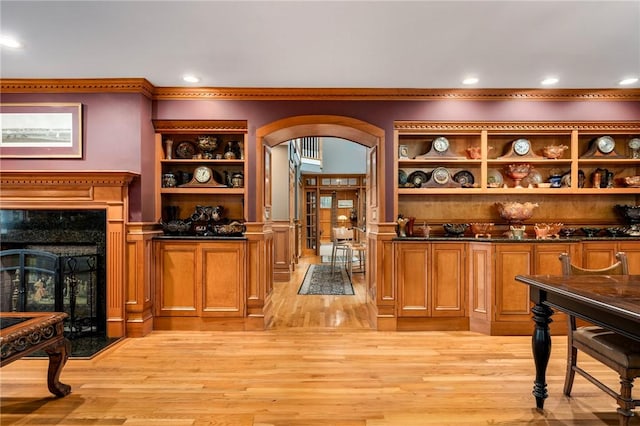 bar featuring arched walkways, a fireplace, and light wood-style flooring